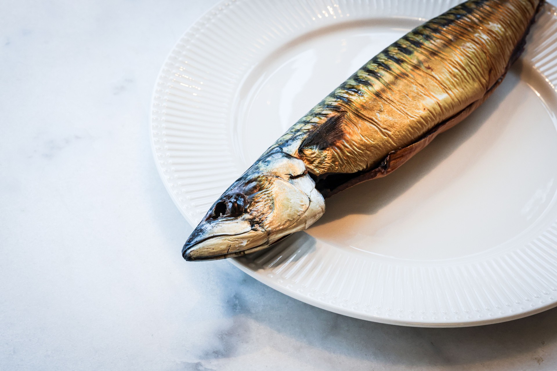 Smoked mackerel on white plate, copy space.